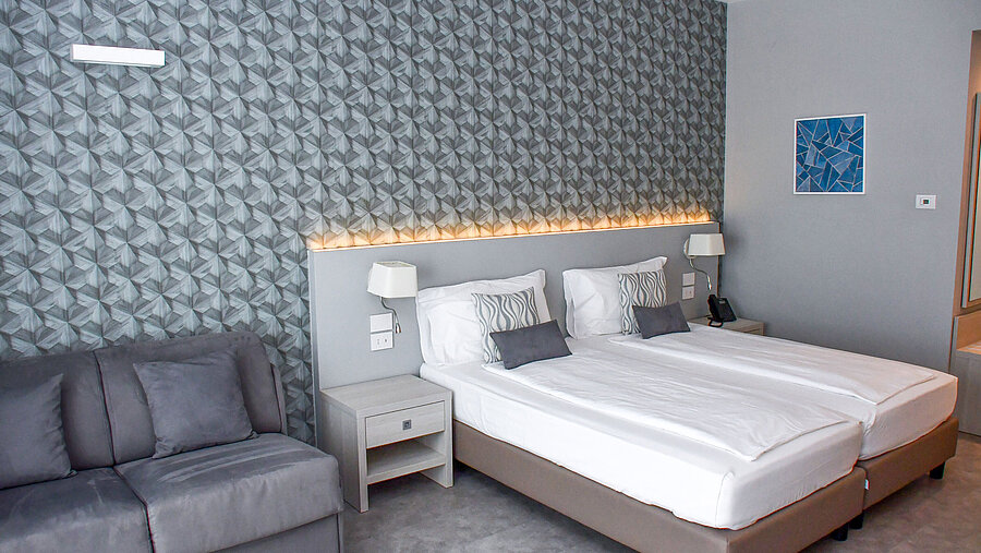 Spacious room at Maritim Resort Calabria with twin bed, sofa and stylish wall design