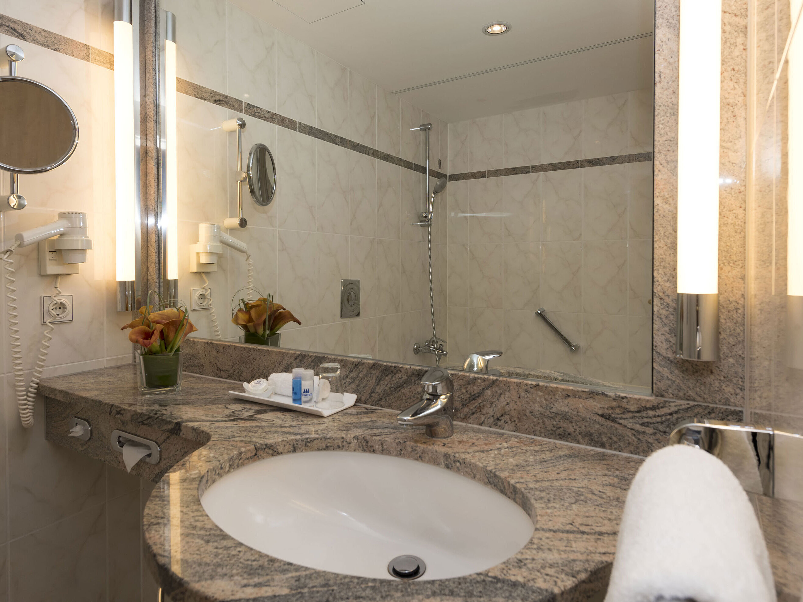Modern bathroom at Maritim Seehotel Timmendorfer Strand with granite sink, mirror, and shower.