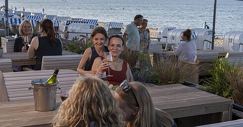 Guests enjoying wine at the beach bar of Maritim Seehotel Timmendorfer Strand with views of beach chairs and the sea.
