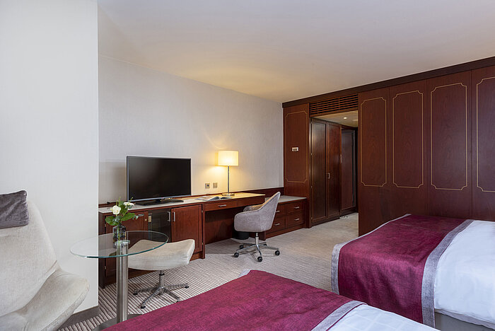 Family room at Maritim Hotel Bonn with modern amenities, comfortable beds, and a convenient desk.
