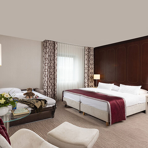 Comfort family room at Maritim Hotel Bonn with a large double bed, pull-out sofa, armchair, and flower arrangement.