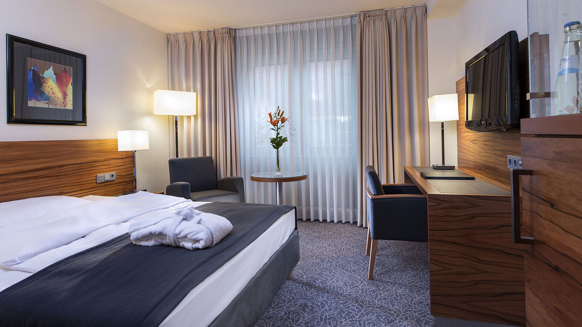 Modern double room at the Maritim Hotel Munich. Comfortably equipped with a large bed, workspace, and armchair.