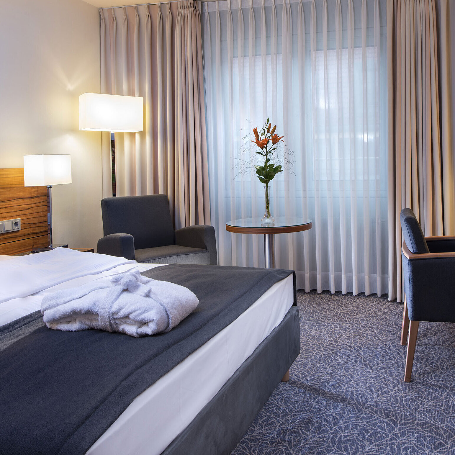 Modern double room at the Maritim Hotel Munich. Comfortably equipped with a large bed, workspace, and armchair.