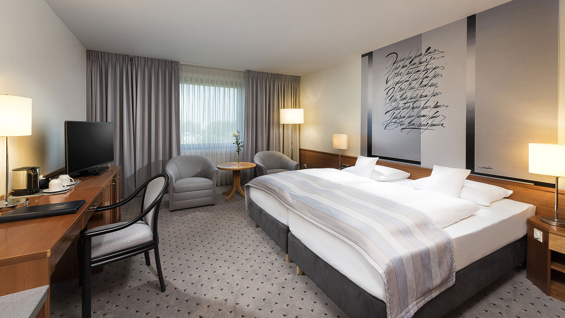 Modern classic double room with a cozy double bed, seating area, and desk at Maritim Hotel Hannover.