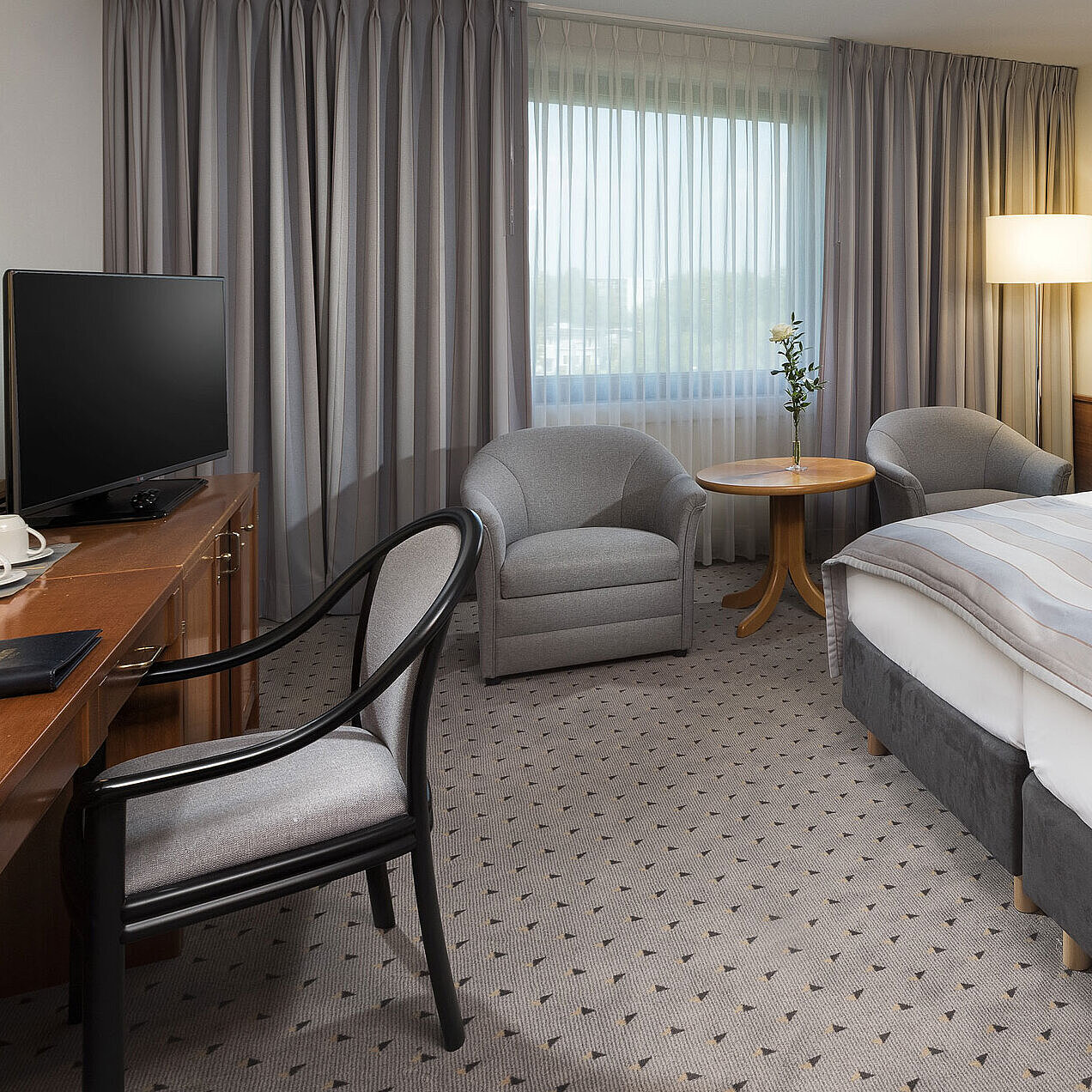 Modern classic double room with a cozy double bed, seating area, and desk at Maritim Hotel Hannover.