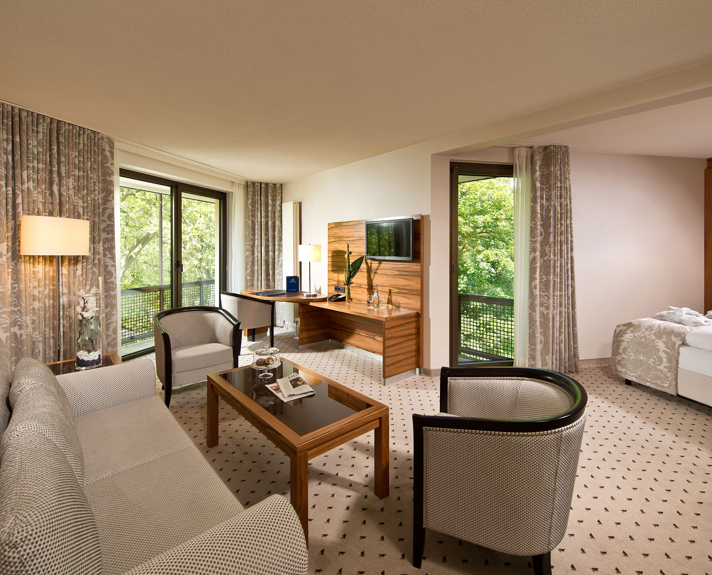 Spacious suite at Maritim Hotel Bad Homburg with separate living area, balcony, and green view.