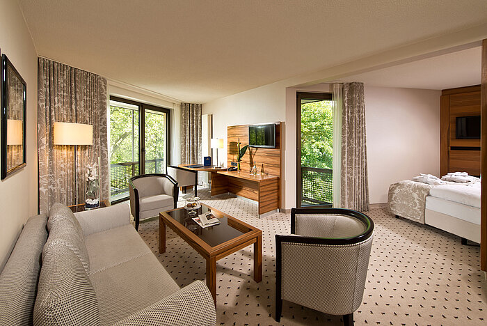 Spacious suite at Maritim Hotel Bad Homburg with separate living area, balcony, and green view.