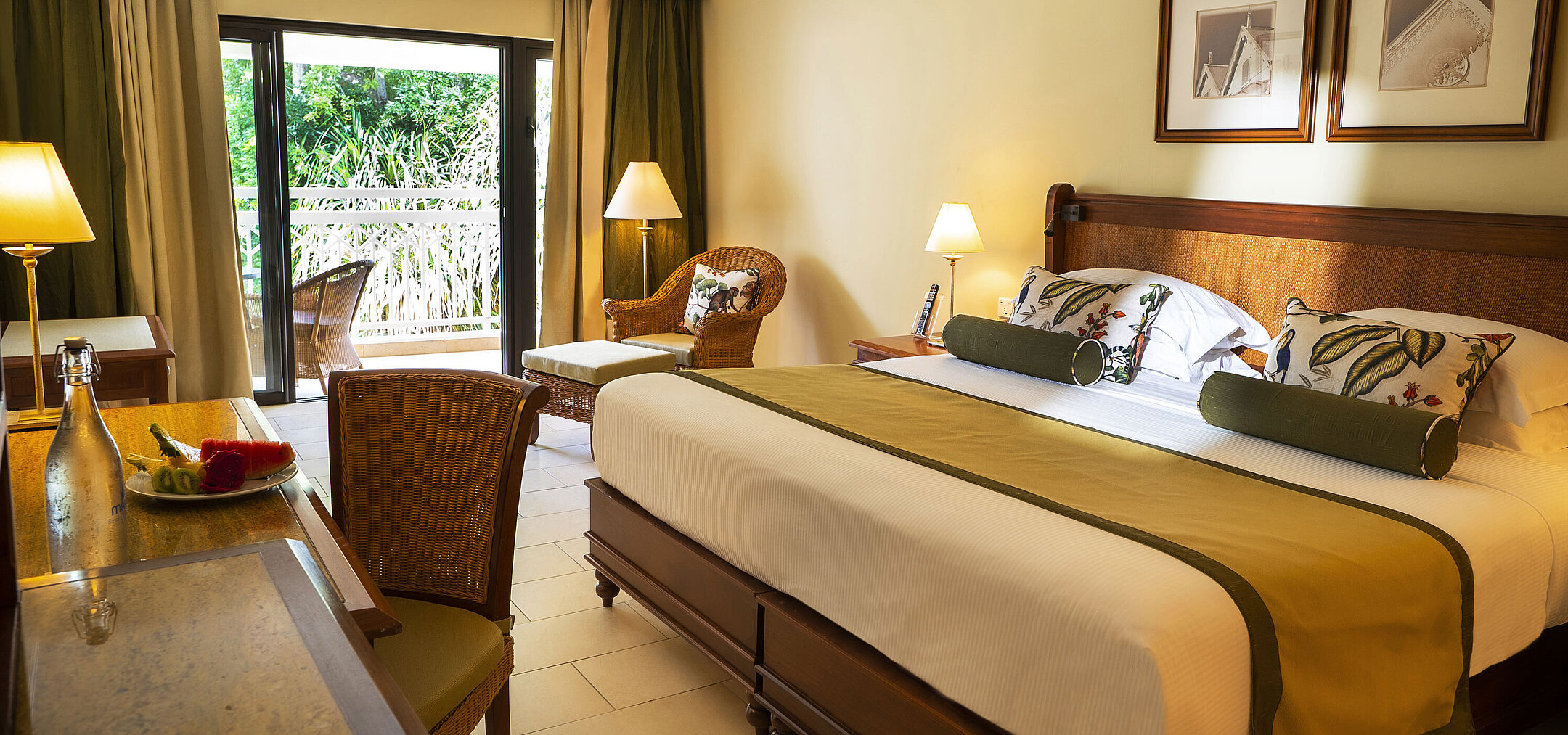 Elegant hotel room with balcony, desk, seating area and green surroundings