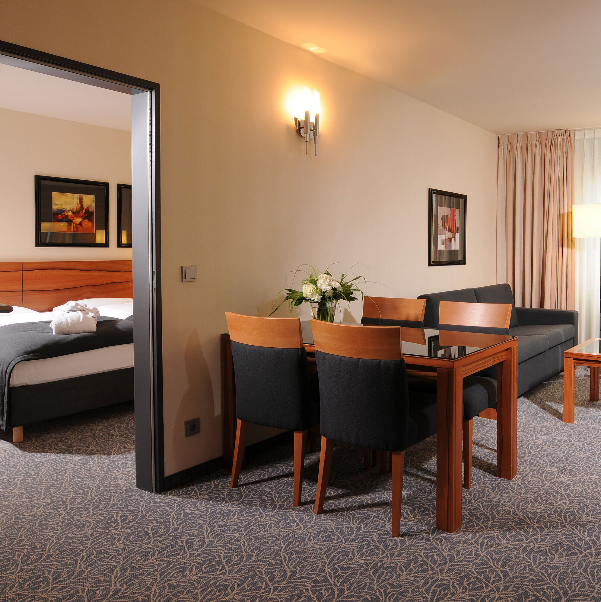 Spacious suite with living room, dining table and separate bedroom at Maritim Hotel Munich