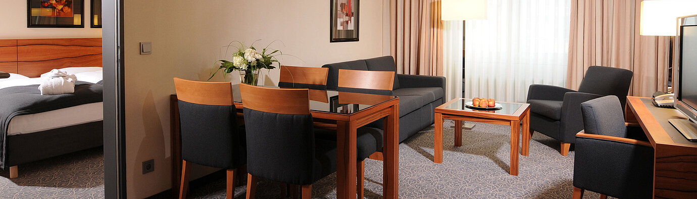 Spacious suite with living room, dining table and separate bedroom at Maritim Hotel Munich
