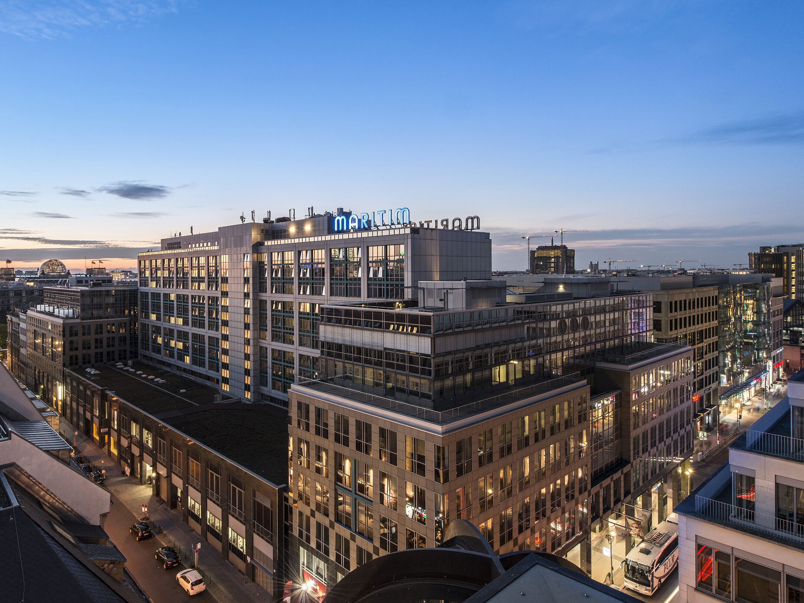View of Maritim proArte Hotel Berlin at dusk, surrounded by modern buildings in the heart of Berlin.