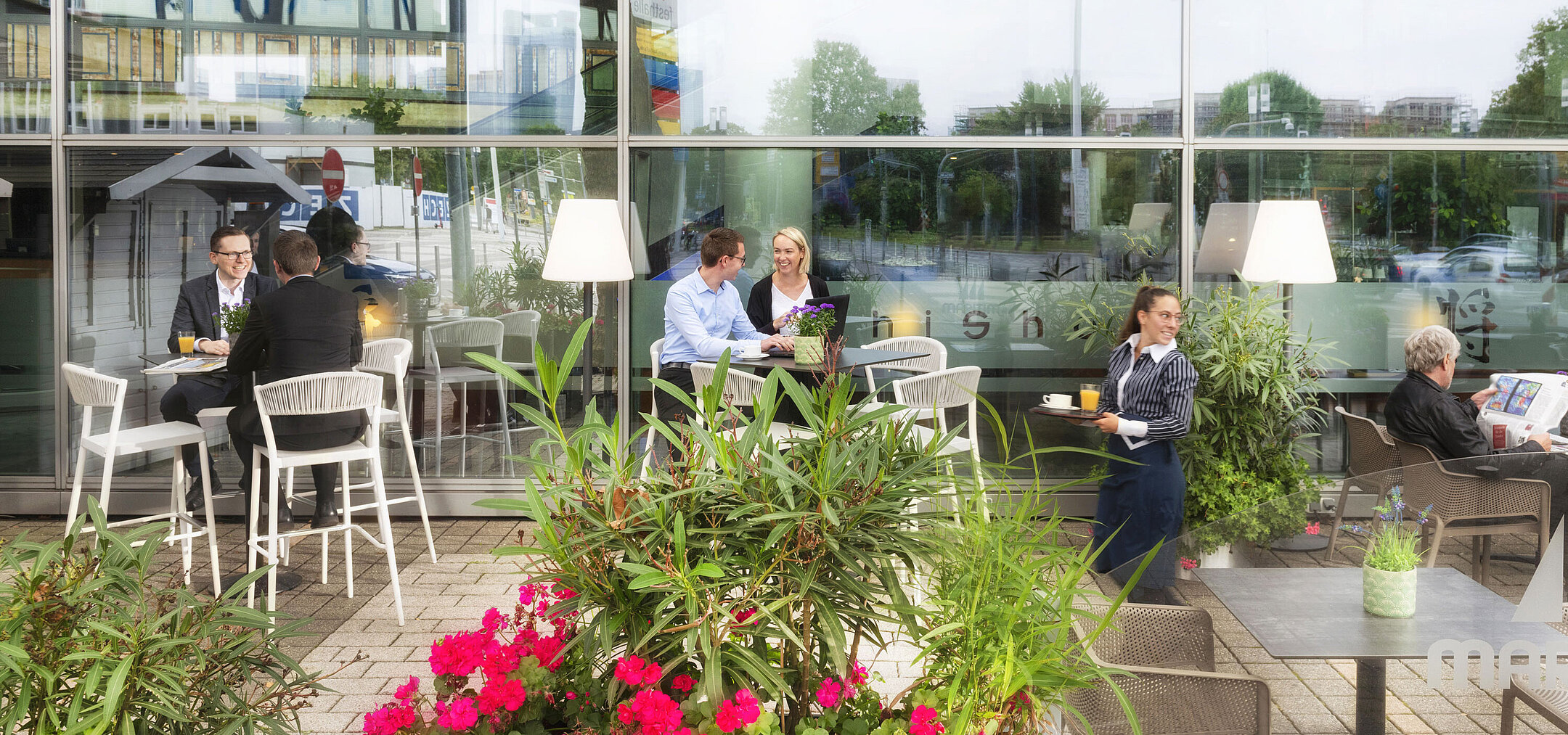 Guests enjoy coffee and conversations on the terrace of the Maritim Hotel Frankfurt with a view of the city.