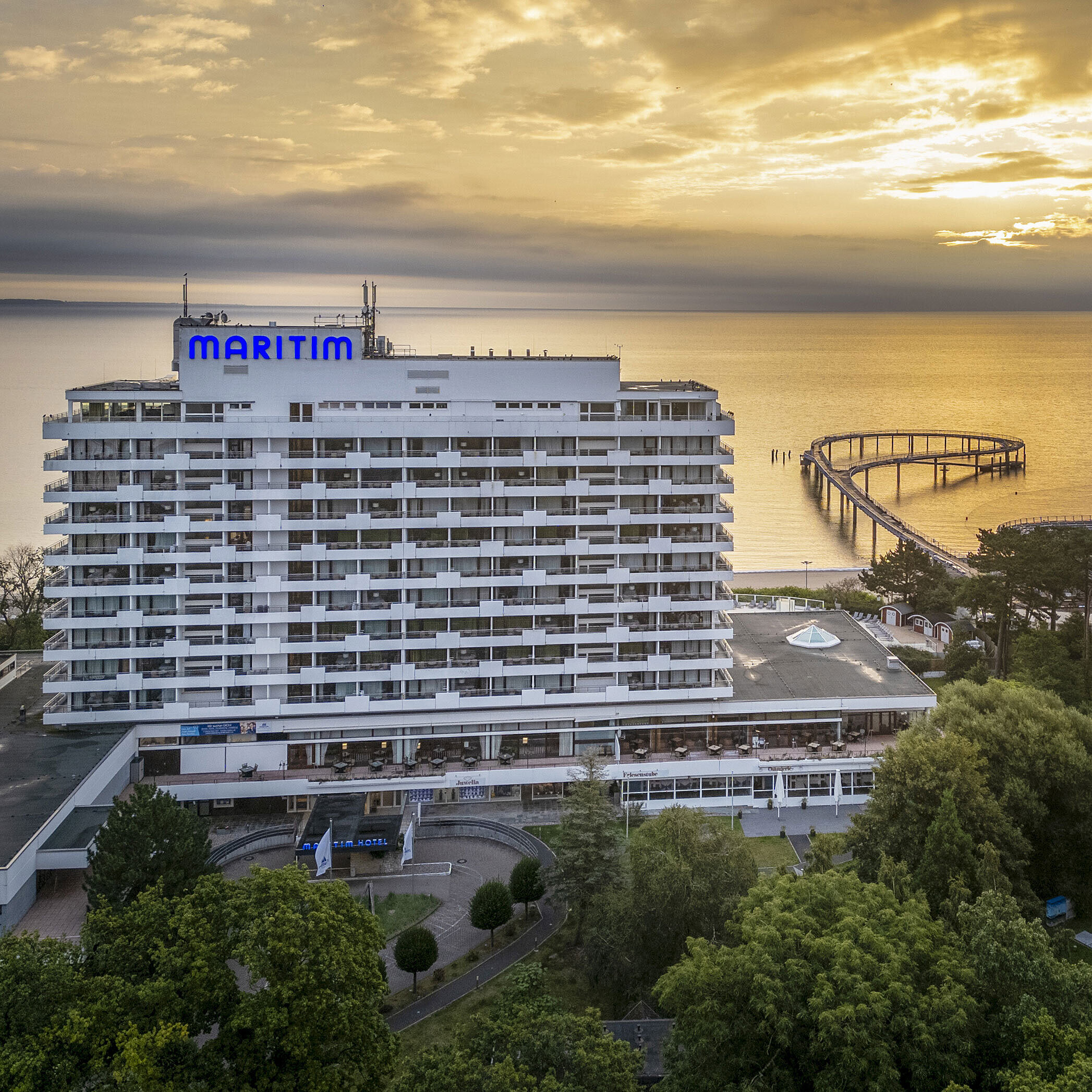 Maritim Seehotel Timmendorfer Strand at sunrise with a pier and sea view.