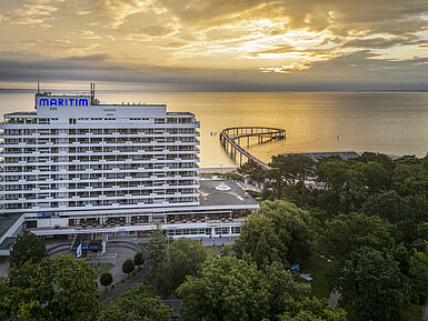 Maritim Seehotel Timmendorfer Strand at sunrise with a pier and sea view.
