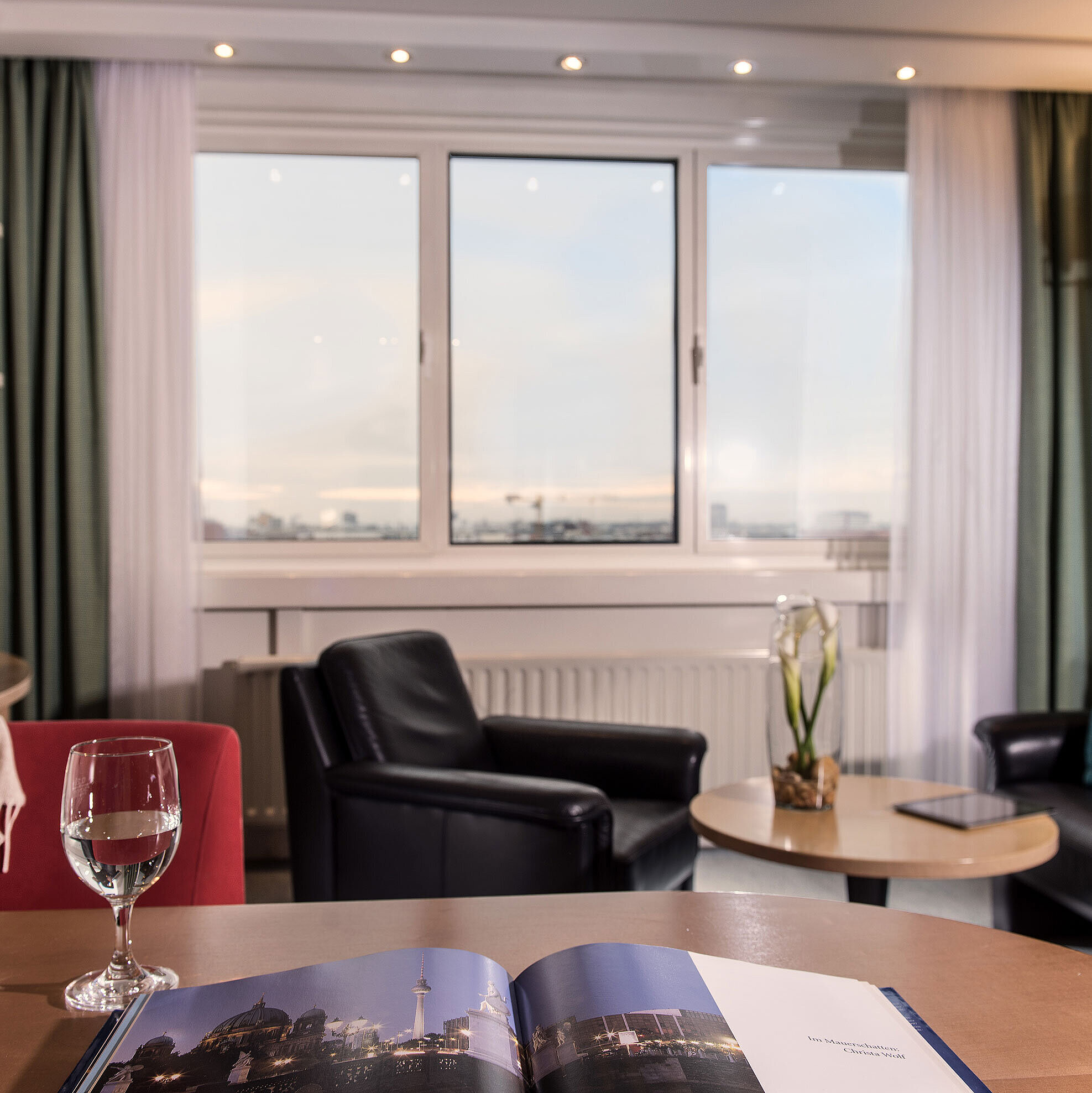  Junior suite at Maritim proArte Hotel Berlin with seating area, city view, and elegant design elements.