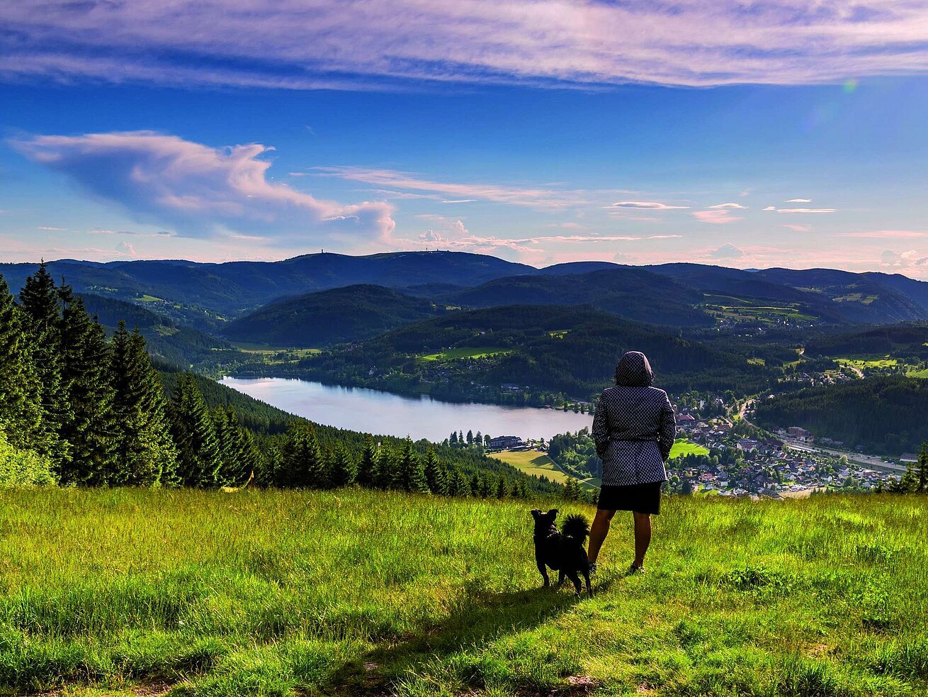 Woman with dog enjoying the view of Lake Titisee and the Black Forest landscape from Hochfirst