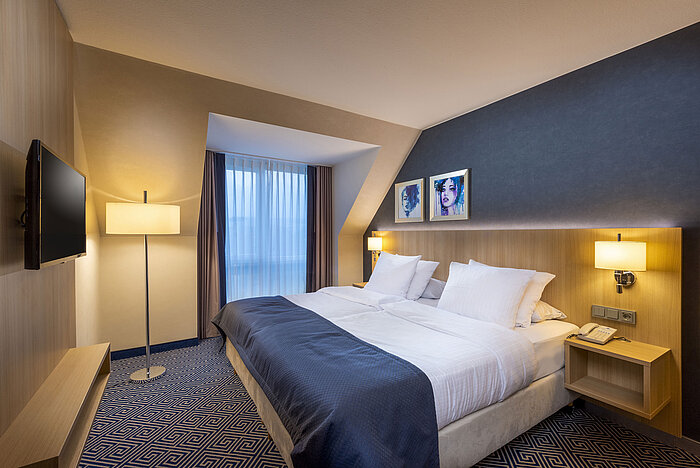Modern double room at Maritim Hotel Würzburg with wall art and warm lighting.
