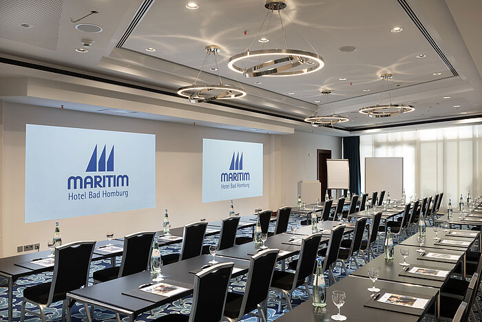 Modern conference room at Maritim Hotel Bad Homburg with seating and projection.