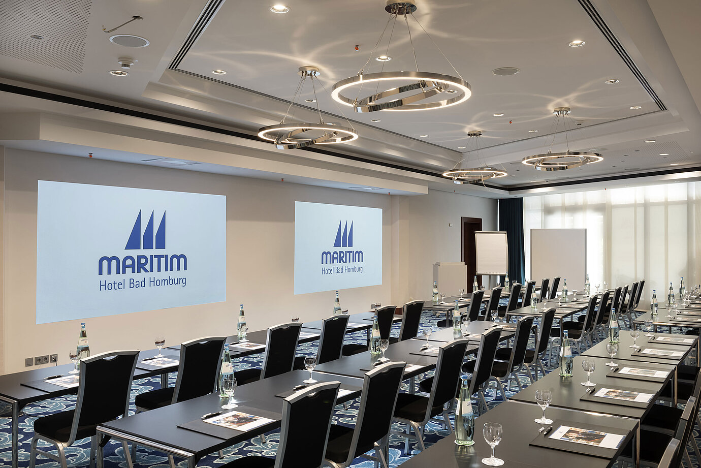 Modern conference room at Maritim Hotel Bad Homburg with seating and projection.