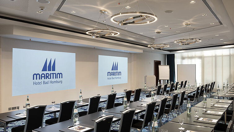 Modern conference room at Maritim Hotel Bad Homburg with seating and projection.