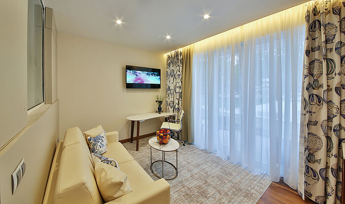 Bright living area with sofa, small table and desk in a modern hotel room