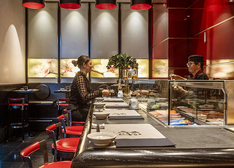 Guest enjoying fresh sushi at the elegant "SushiSho" sushi bar in Maritim Hotel Düsseldorf with authentic ambiance.