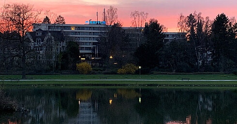 Exterior view of Maritim Hotel Bad Salzuflen at dusk with reflections in the water and atmospheric lighting.