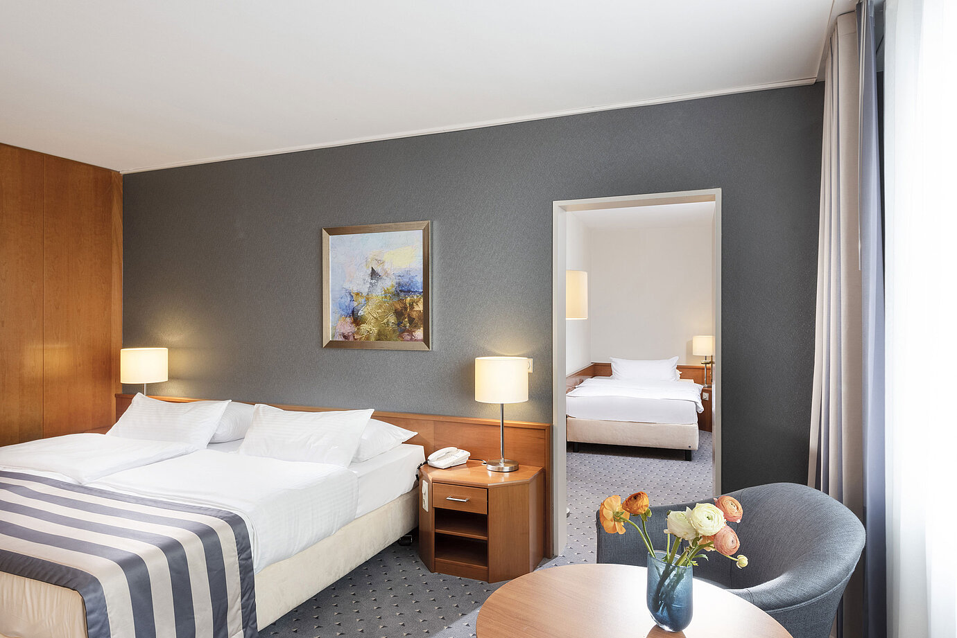 Family room at Maritim Hotel Ulm with double bed, seating area and elegant mirrored wall