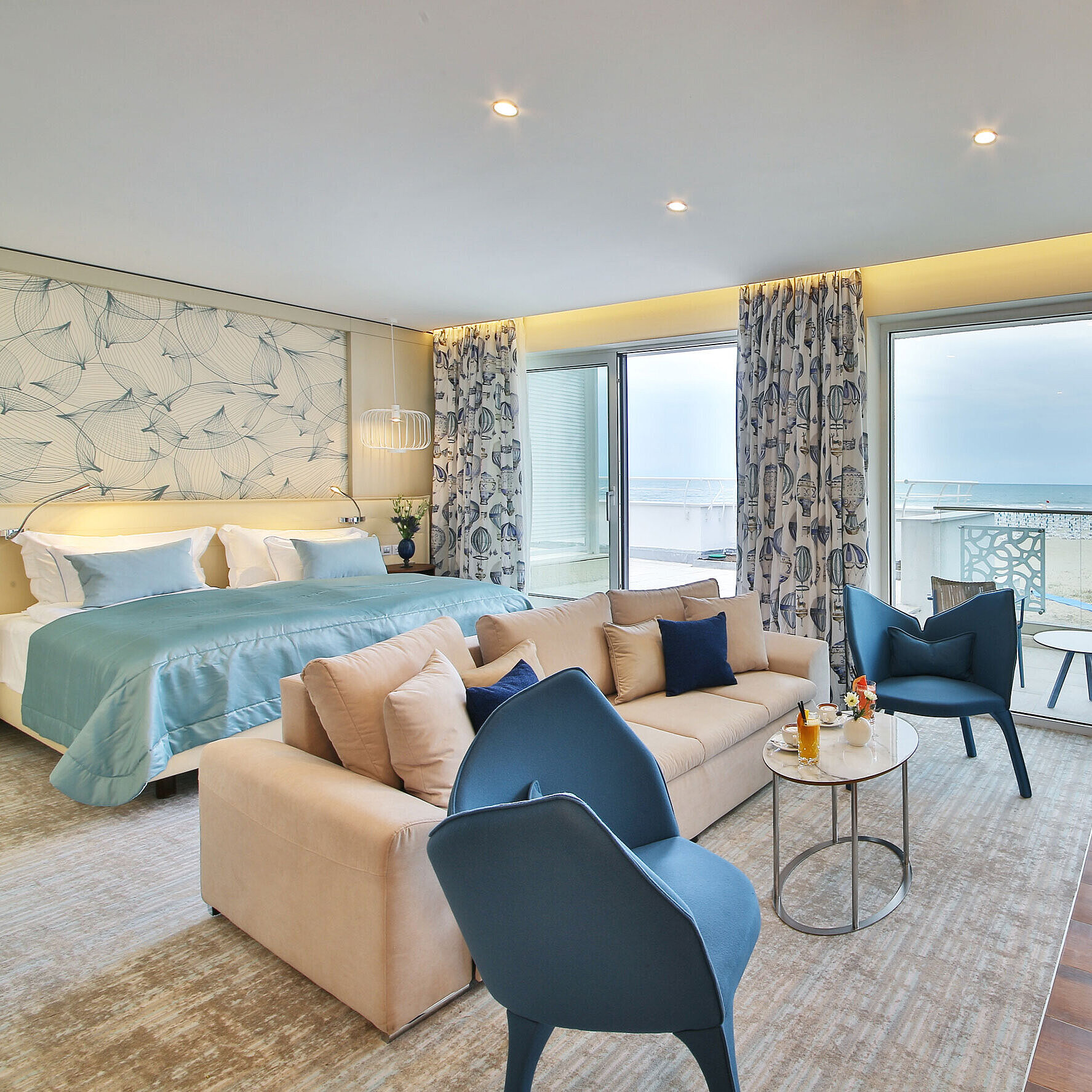 Suite with large bed, seating area and balcony with sea view in a modern hotel