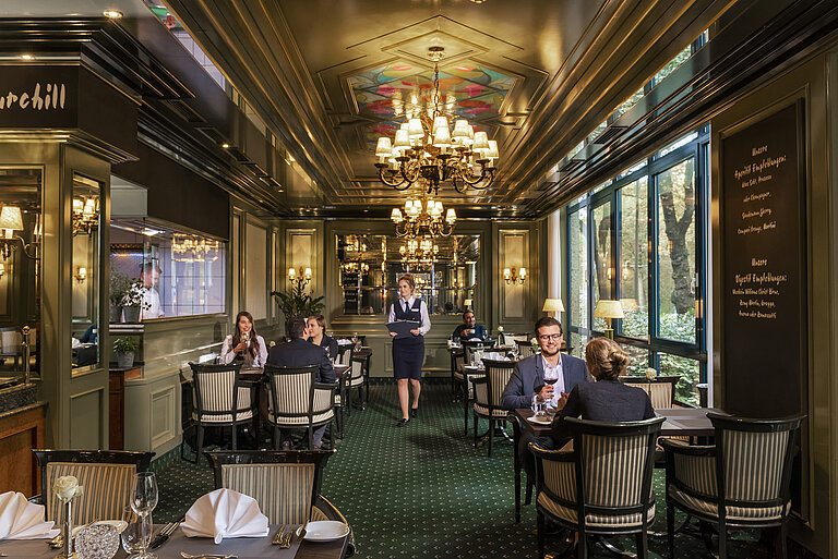 Guests enjoying fine dining in the elegant L'Echalote restaurant at Maritim Hotel Bremen's stylish setting.