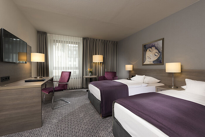 Modern twin room at Maritim Hotel Königswinter with two beds, desk, and stylish decor.