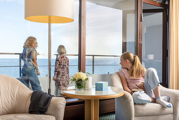 Children enjoy the sea view from the family suite at the Maritim Hotel Timmendorfer Strand, while one girl reads in the chair