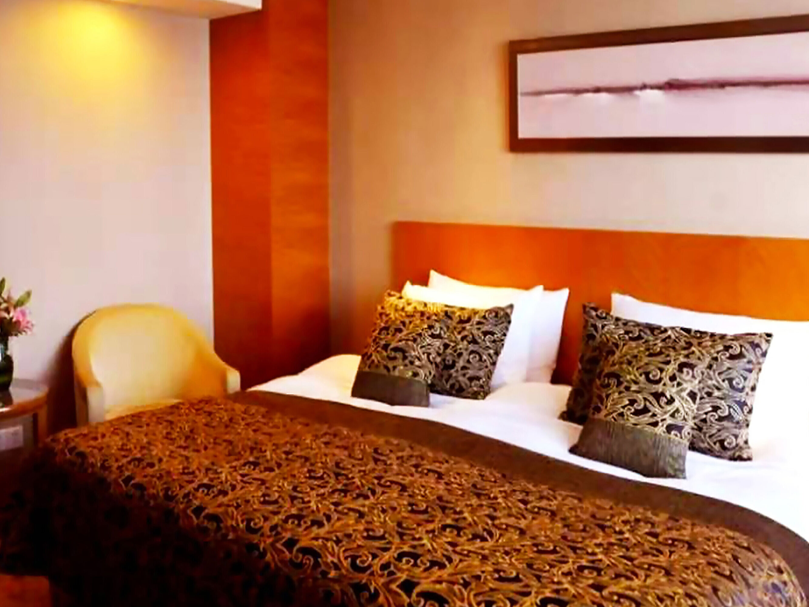 舒適的酒店客房配備寬敞大床、裝飾抱枕、暖色調裝潢及休閒扶手椅，讓您享受放鬆的住宿體驗