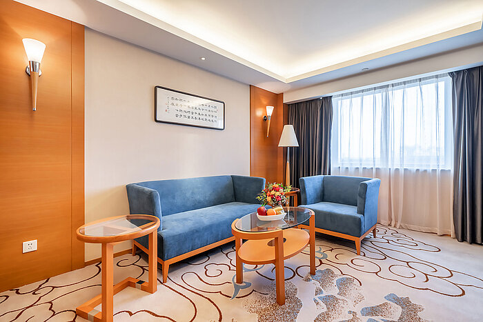 現代化休憩區配備藍色沙發、扶手椅、玻璃茶几、花卉擺設，並設有大型窗戶引入充足自然光線