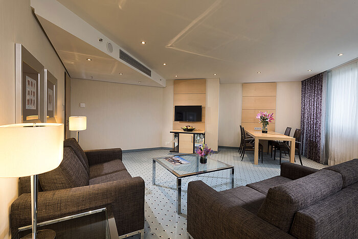Spacious suite at Maritim Hotel Düsseldorf with modern living area, dining table, sofas, and stylish decor.