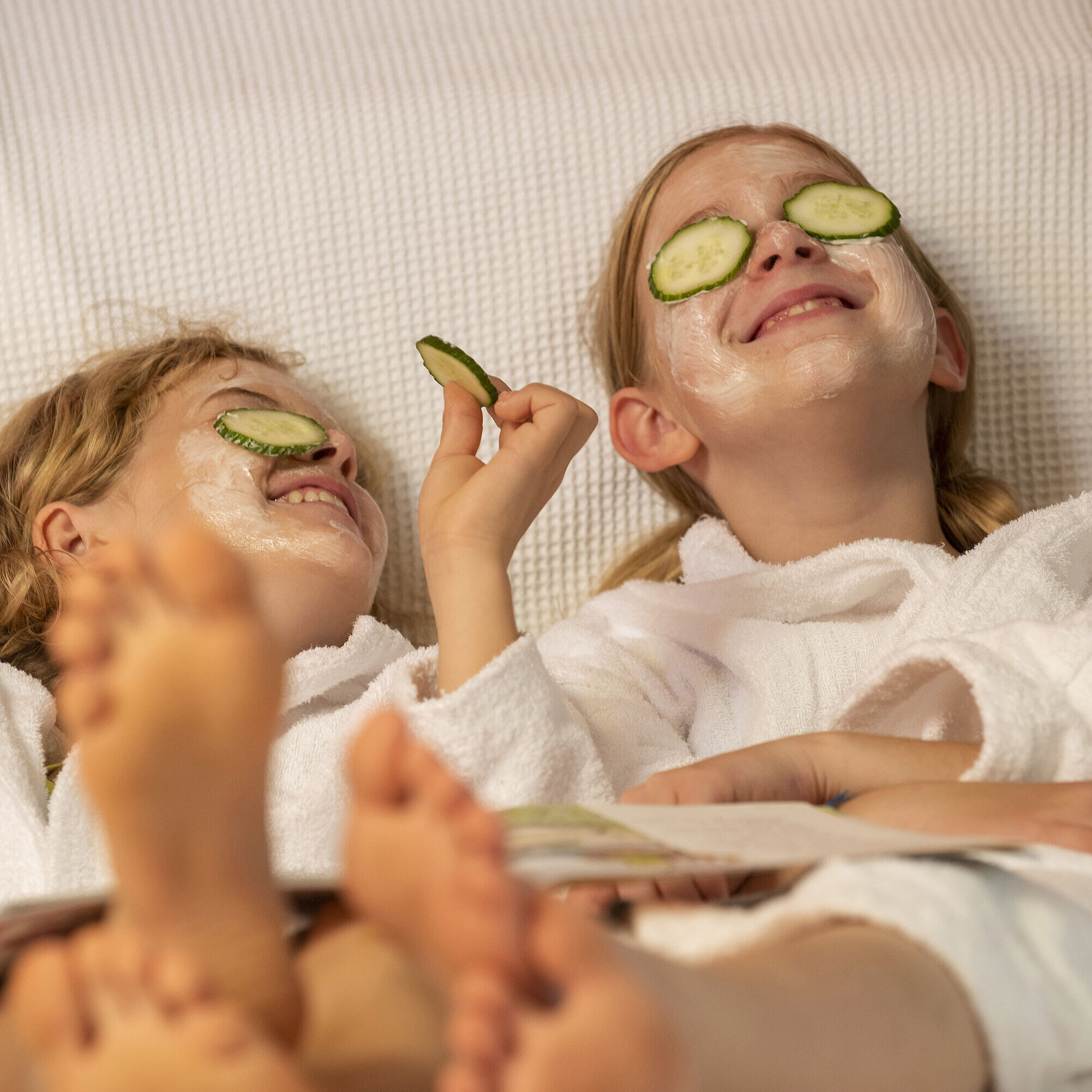 Two girls with facial masks and cucumber slices relax at the Maritim Hotel Spa, enjoying their treatment.