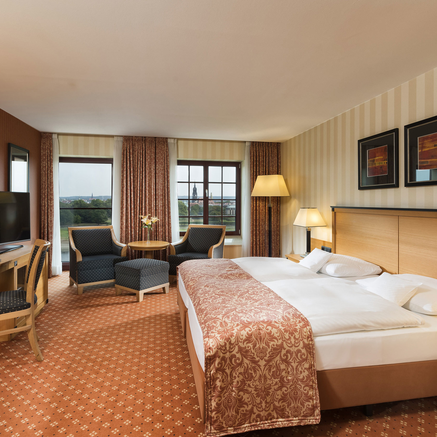 Superior room at Maritim Hotel Dresden with elegant double bed, desk, and seating area with city view.
