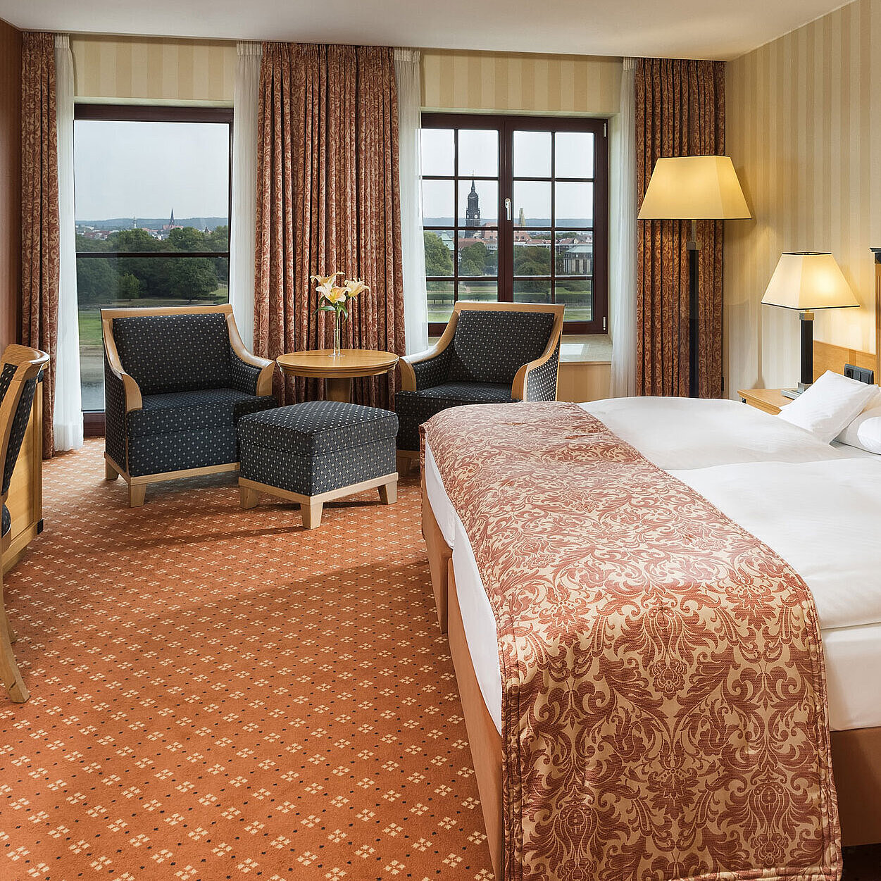 Superior room at Maritim Hotel Dresden with elegant double bed, desk, and seating area with city view.