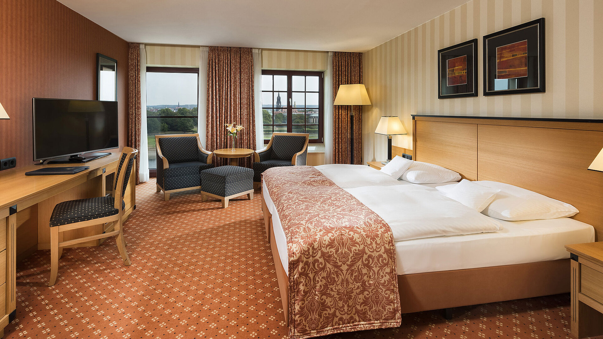 Superior room at Maritim Hotel Dresden with elegant double bed, desk, and seating area with city view.