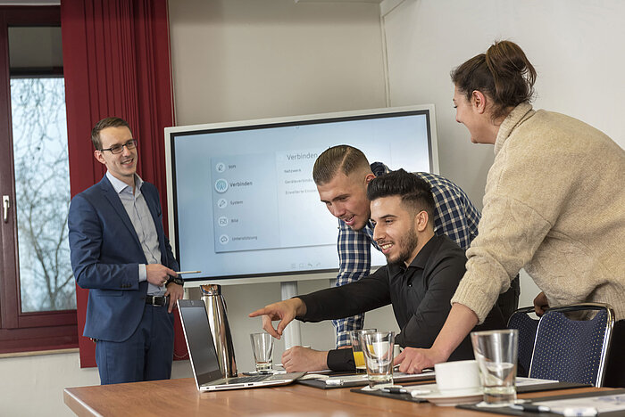 Team meeting in Salon Rhein at Maritim Cologne with a screen, laptops, and participants collaborating and presenting.