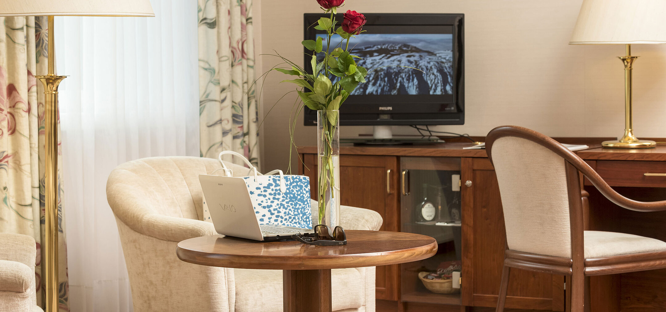 Cosy seating area with roses, laptop and TV in the room of Maritim Hotel Bad Wildungen