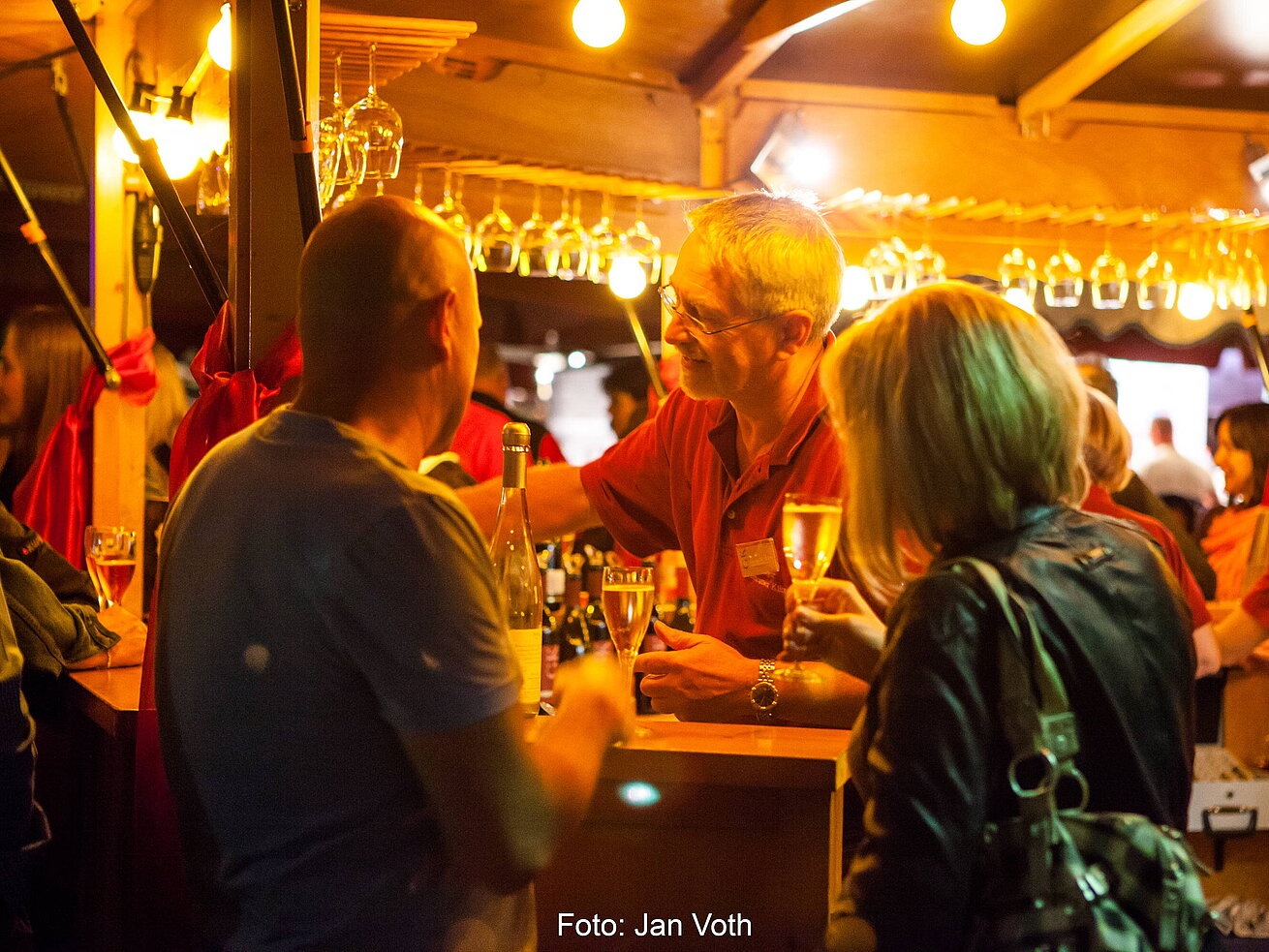 Wine festival Bad Salzuflen Visitors enjoying a wine festival in Bad Salzuflen with illuminated stalls and a lively atmosphere.