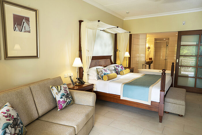 Bright hotel room with double bed, balcony, seating area and warm lighting at Maritim Hotel