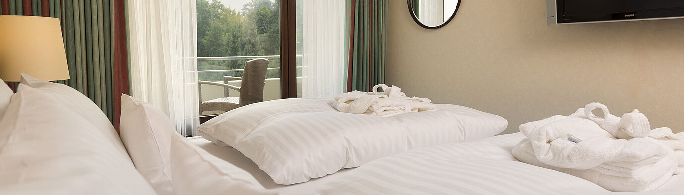 Double bed with TV, bathrobe and balcony view at Maritim Hotel Bad Salzuflen