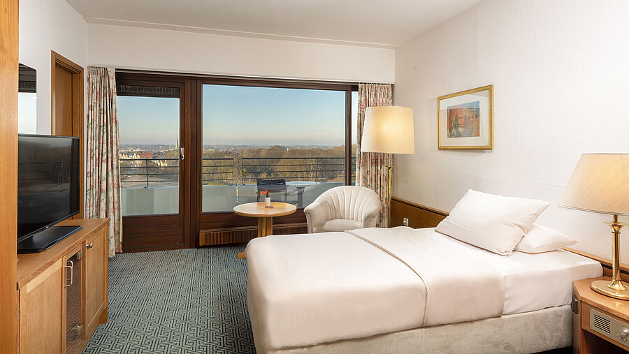 Single room with cosy bed, armchair and balcony with view over Travemünde and Lübeck Bay