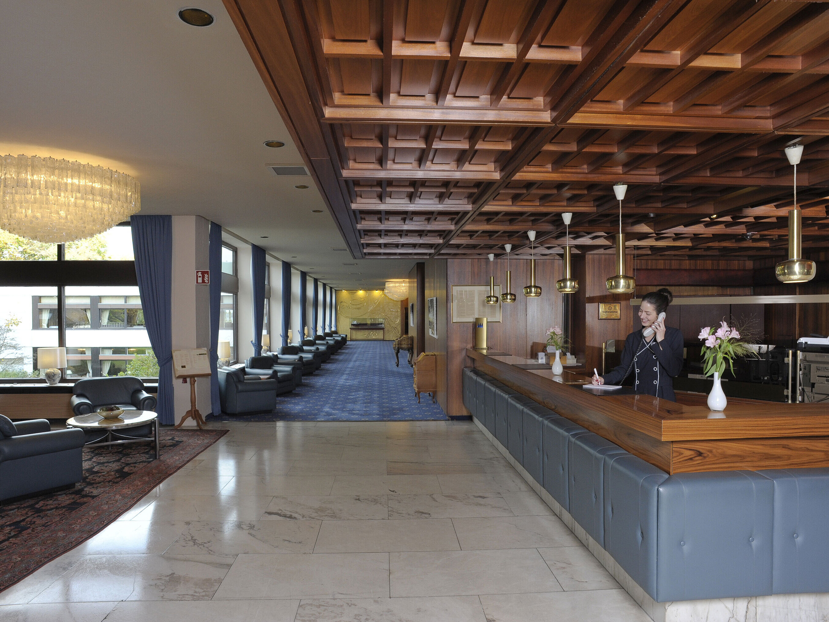 Reception at the Maritim Hotel Kiel, elegant wood paneling, chandeliers and cozy seating areas with views of large windows