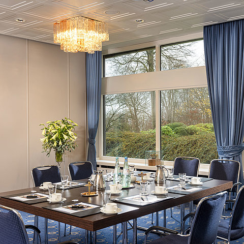 Salon Flensburg in the Maritim Hotel Kiel, conference room with a set table, large windows and stylish lighting.