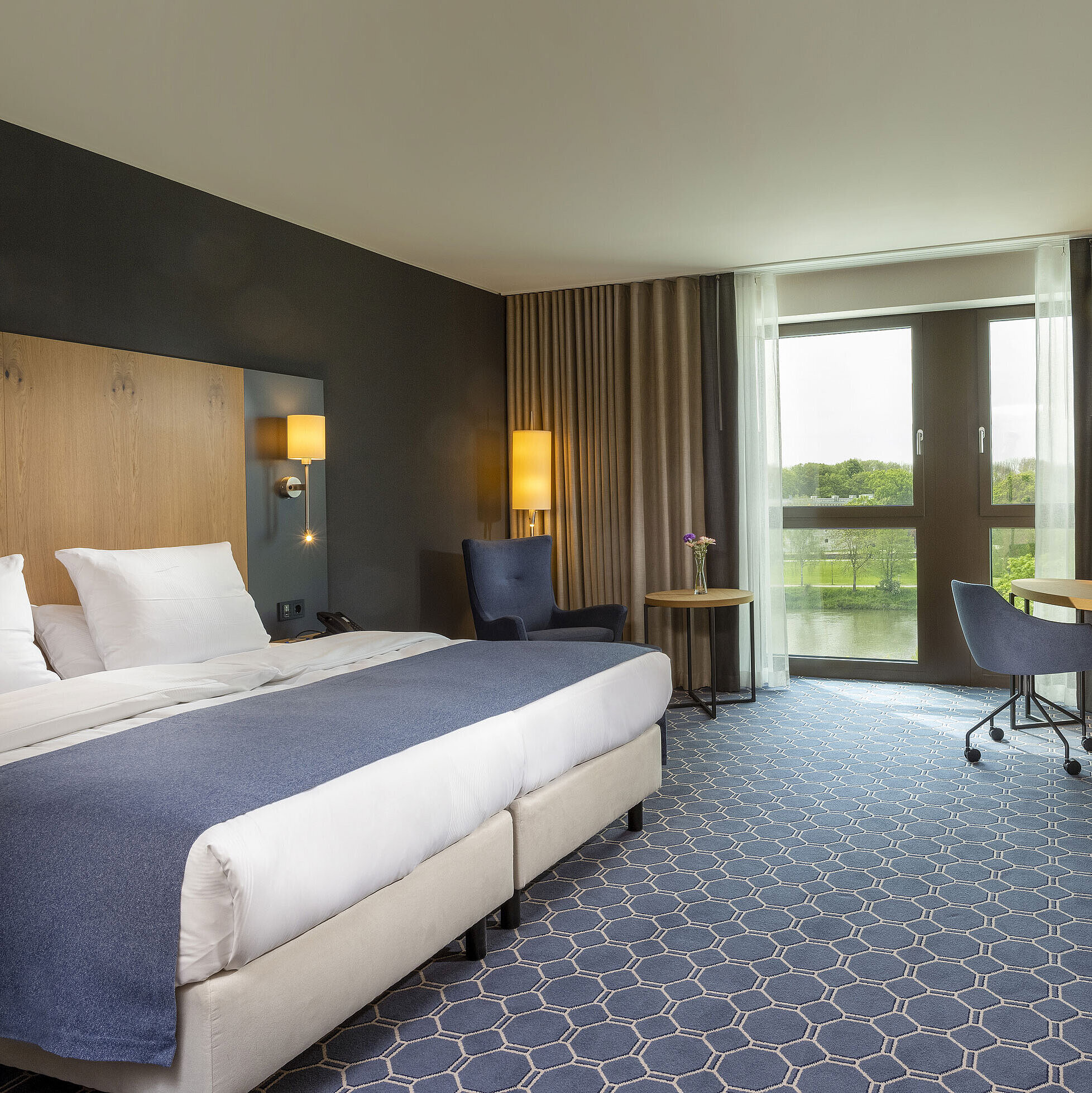 Spacious double room at Maritim Hotel Ingolstadt with bed, desk, and a view of the river.