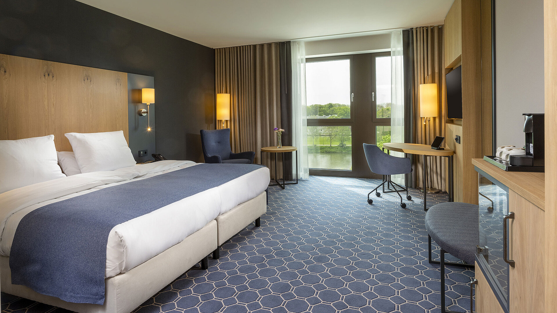 Spacious double room at Maritim Hotel Ingolstadt with bed, desk, and a view of the river.