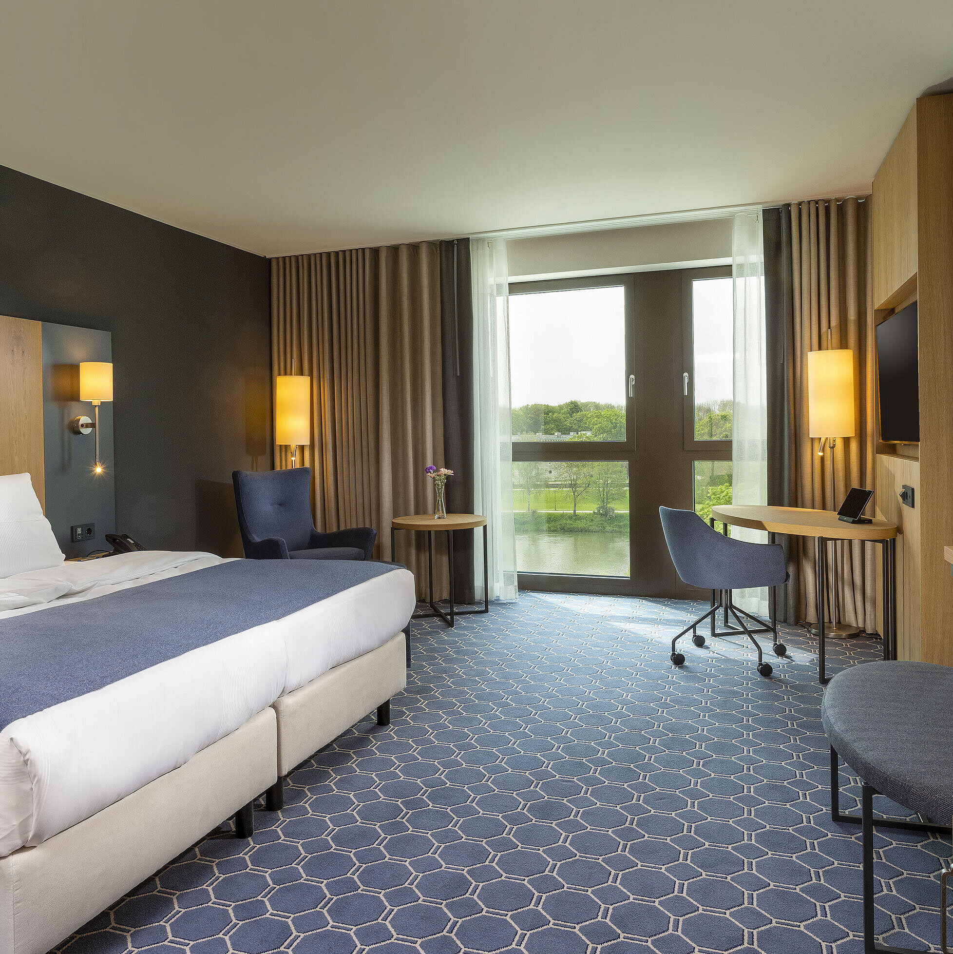 Spacious double room at Maritim Hotel Ingolstadt with bed, desk, and a view of the river.